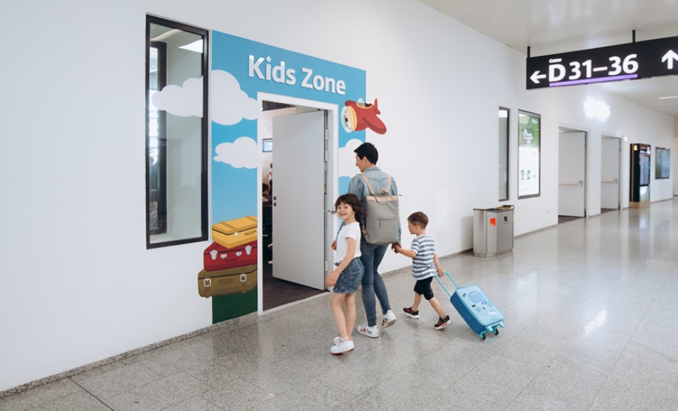 Family enters the colorful Kids Zone at the airport near gates D31–36