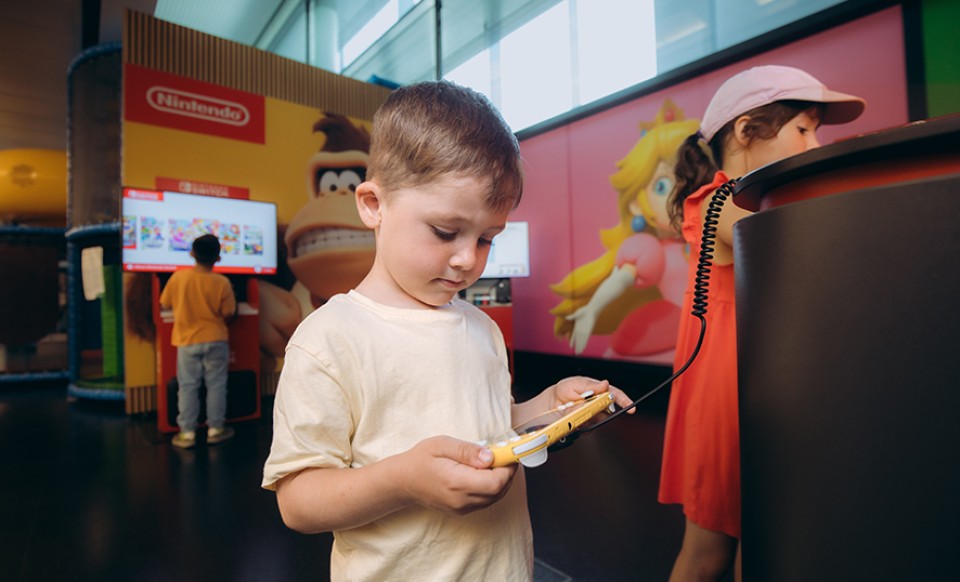 Child plays with handheld console in the Nintendo gaming area at the airport