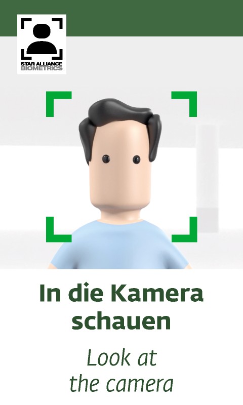 Ein vereinfachtes, animiertes Gesicht ohne erkennbare Gesichtszüge wie Mund oder Nase. Es hat eine glatte, beige Hautfarbe mit schwarzen, runden Augen und dunklem, welligem Haar. Die Person trägt ein hellblaues T-Shirt. Um das Gesicht herum befinden sich grüne Ecken, die einen Erkennungsrahmen darstellen, möglicherweise zur Gesichtserkennung.