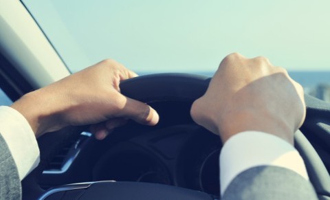 Nahaufnahme von Händen am Lenkrad während der Autofahrt, Blick aus dem Fahrzeuginneren.