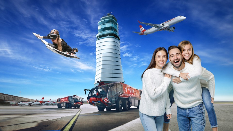 Familie am Flughafen Wien vor Tower, mit Feuerwehrfahrzeugen, Flugzeug und VR-Flugsimulator im Hintergrund.
